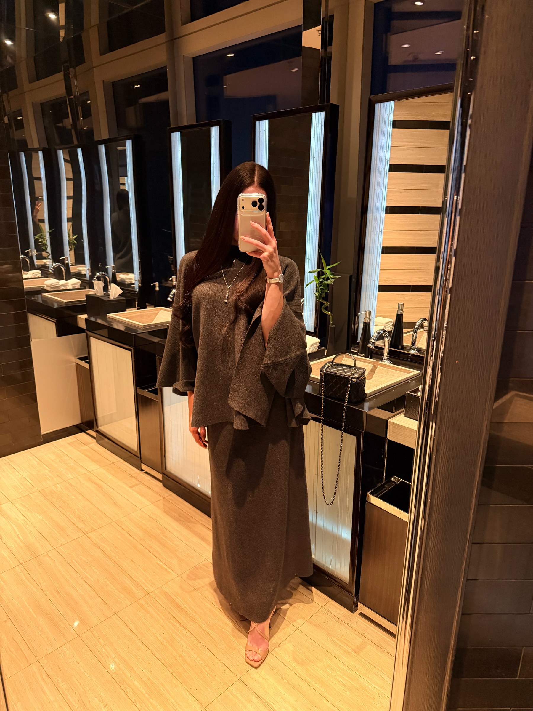 Irina, a mirror selfie in a chocolate-brown knit outfit and heels in a warmly lit bathroom