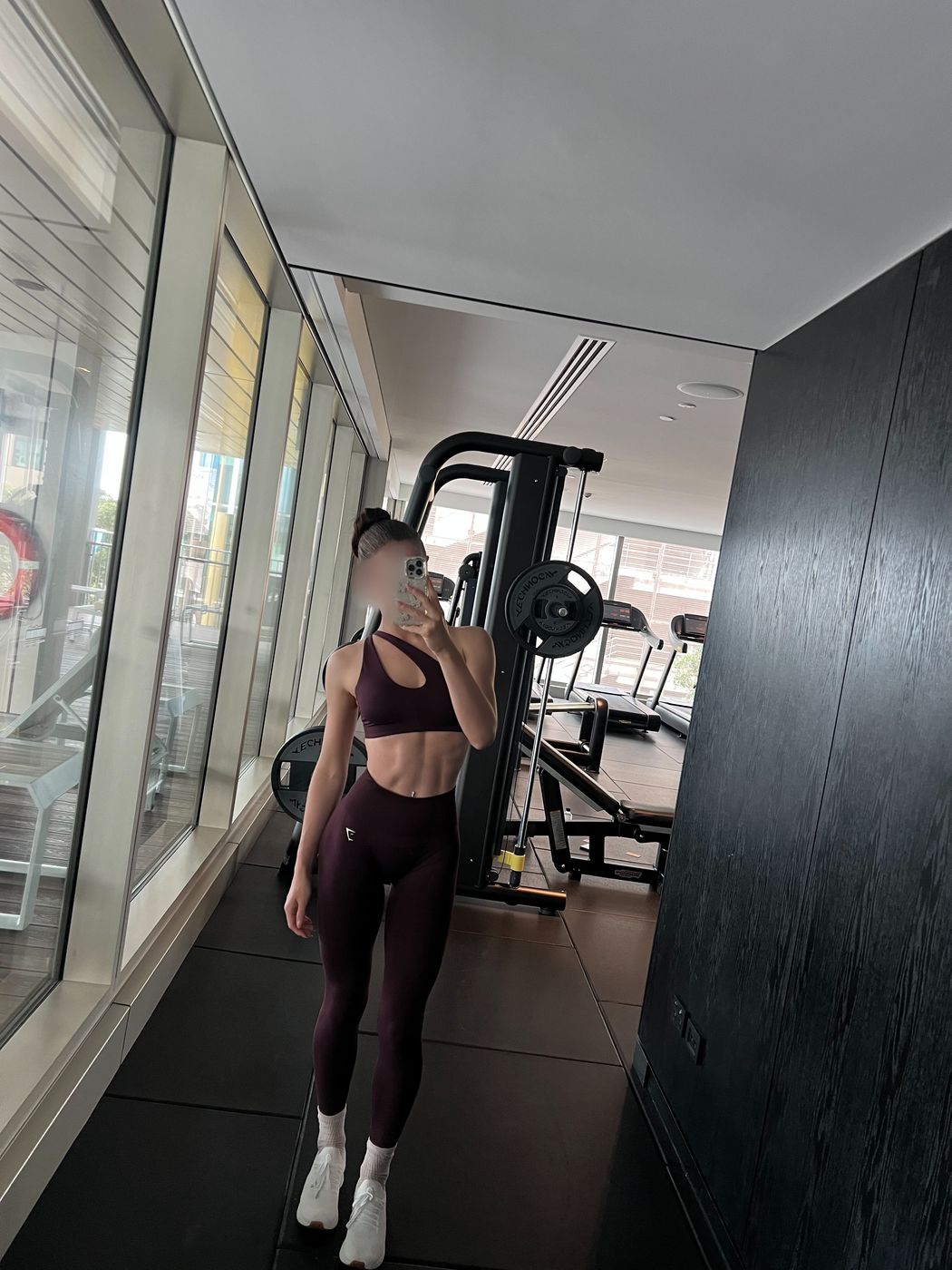Irina, a gym mirror selfie in a burgundy activewear set and trainers